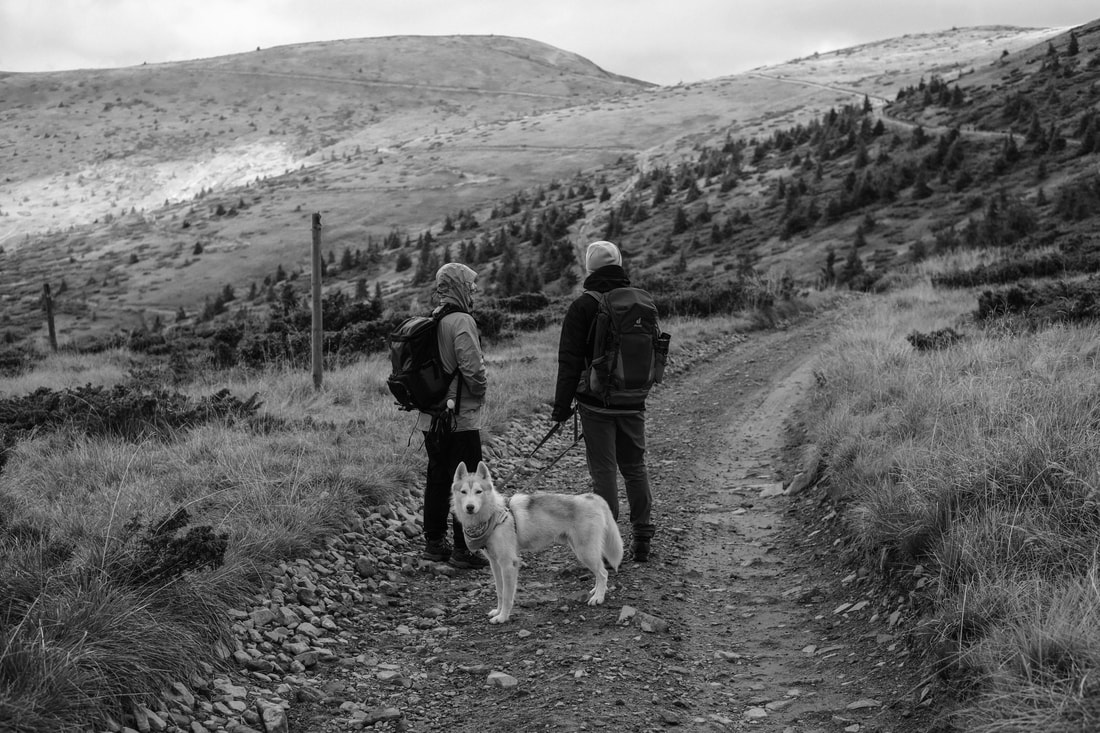 BW woman and man on trail with dog